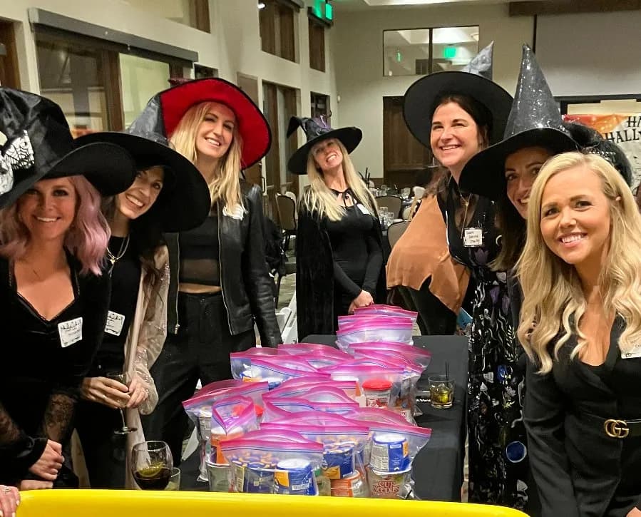 Six witches assembling pink Weekend Meal Kit bags at the 2025 event